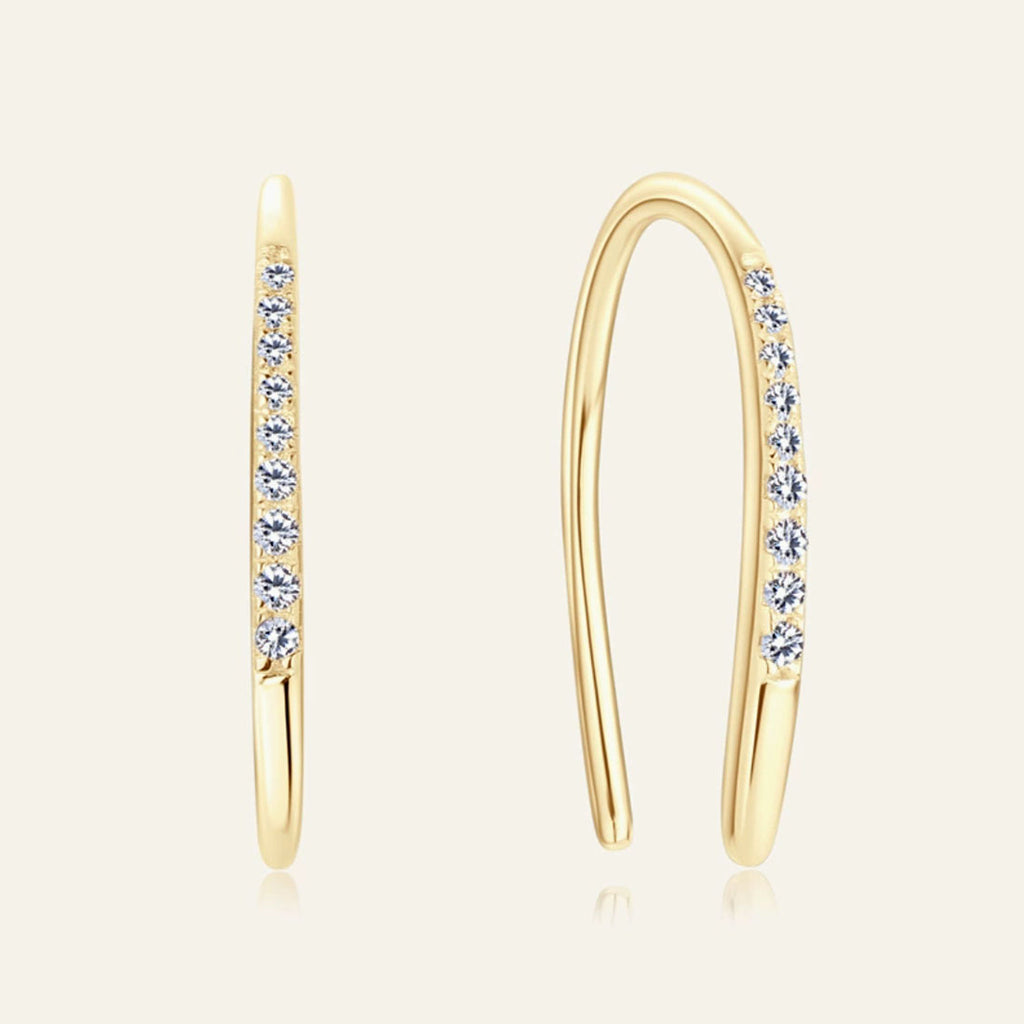 Gold hoop earrings with embedded diamonds on a light beige background