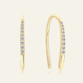 Gold hoop earrings with embedded diamonds on a light beige background