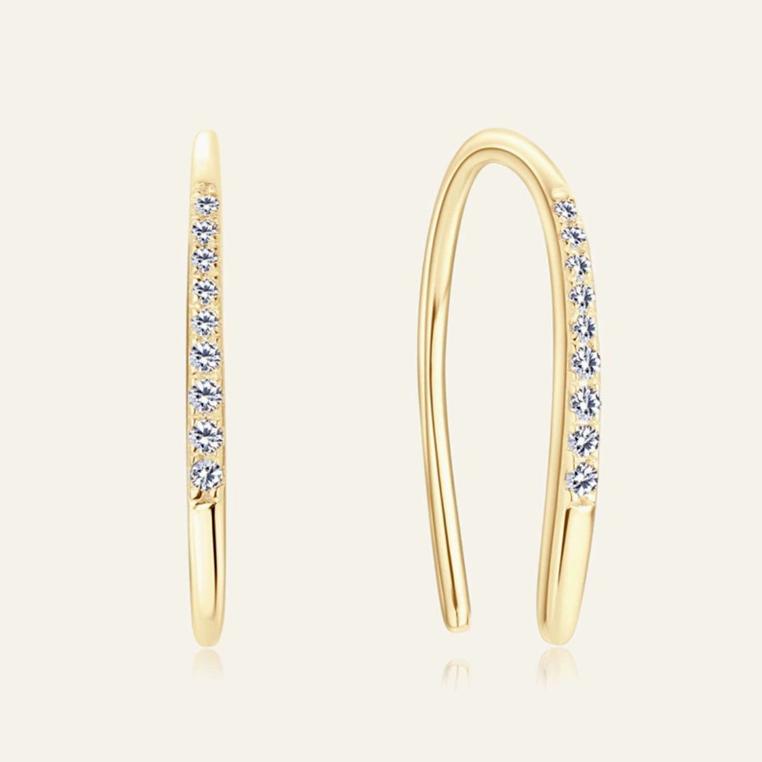 Gold hoop earrings with embedded diamonds on a light beige background